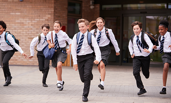 secondary school children in uniform running out of a school building 