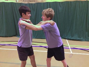 two children in purple shirts holding each other's shoulders in a gym